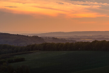 Naklejka na ściany i meble Sunrise over the mountain area covered with fog orange rays penetrate the landscape.