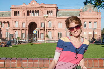 A young woman poses in the city of Buenos Aires with the Presidential Palace in the background.