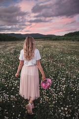 the girl holds a bouquet of pink peonies in her hand