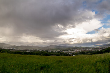 Obraz premium Landscape view of the town of Valasske Mezirici during the rain in the hills on the horizon where the sun shines into the landscape.