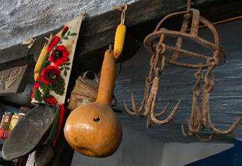 Decorative pumpkin, gourd, corn and metal hooks hanging from the ceiling. Interior of an old country house.