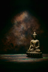 Statuette of Buddha on a dark background.