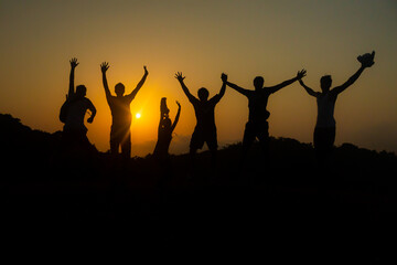 Group of friends jumping in joy over success - silhouette sunset