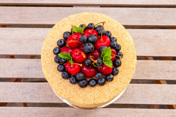 Cake with walnuts, prunes, and honey with a delicate buttercream decorated with fresh blueberries and cherries