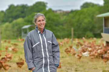 Portrait of a smiling female farmer standing in the middle of her chicken farm