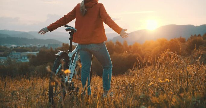 Woman in bicycle helmet with bike rides in country, Happy traveler girl biking in park on sunny summer day. Active healthy outdoor sport fun activity. Freedom, Travel, Journey.