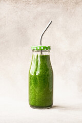 Green smoothie with spinach in small bottle with metal straw. Copy space. Healthy lifestyle concept