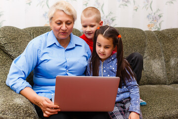 Grandmother with grandchildren using laptop at home