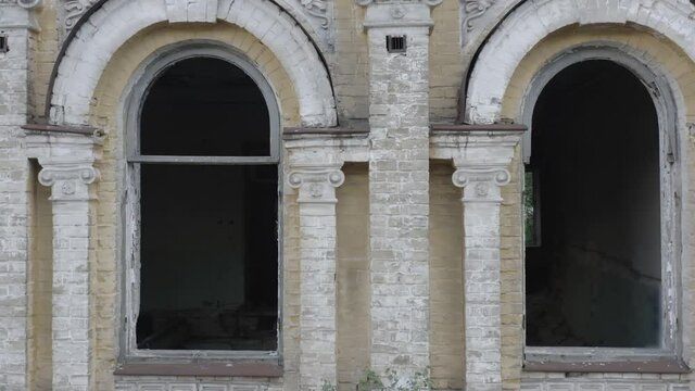 Broken arched windows of an abandoned old manor house (mansion house). Deserted 19th century building. Aerial side view. Close-up shot