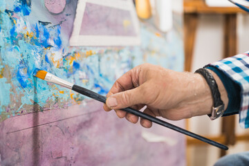 Aged man painting picture with brush