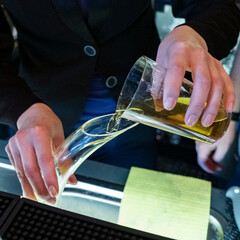 View of sommeliers hand pouring wine from decanter at wine store. Wine concept.