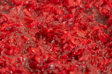 Raw grated beets stewed in a pan, steam, background