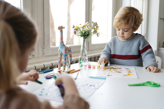 Preschool brother and sister painting together at home
