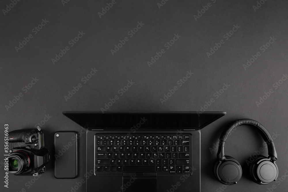 Fototapete creative dark flat lay with camera and laptop on black minimal table background with copy space