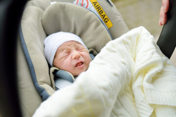 Sweet baby boy crying in a car seat. Newborn being carried in a car seat.