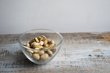 Pistachios in a small plate on a vintage wooden table. Pistachio is a healthy vegetarian protein nutritious food. Natural nuts snacks.