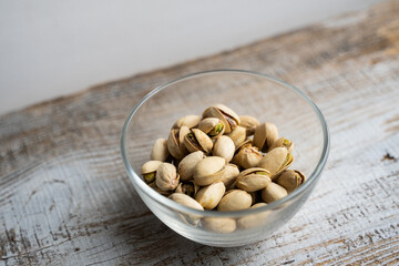 Pistachios in a small plate on a vintage wooden table. Pistachio is a healthy vegetarian protein nutritious food. Natural nuts snacks.
