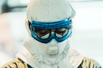 Serious professional doctor in protective uniform and mask standing in modern operating room