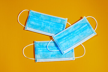 94/5000group of three blue single-use masks for virus protection on yellow background