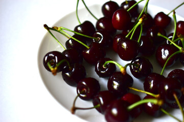 Fruits of ripe red and delicious cherries on a white plate