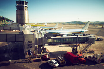 High angle of New York airport with airplanes with jet bridge and machinery on ground in bright sunlight