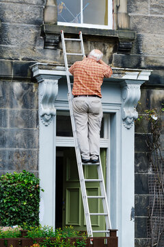 Senior anonymous man repairing door of old mansion