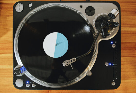 Top view of contemporary vinyl record player with retro disc placed on wooden table in living room