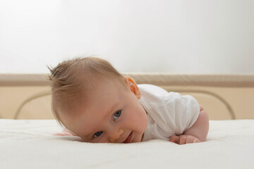 Cute happy newborn baby learning to sit on her tummy. Smiling baby with blue eyes.