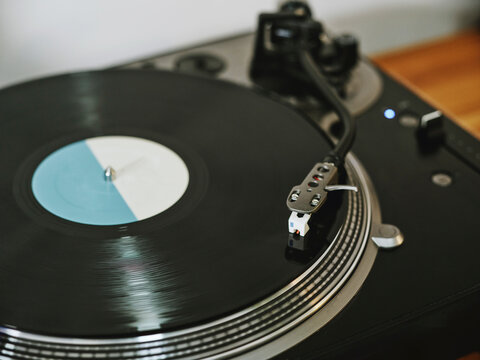 From above contemporary vinyl record player with retro disc placed on wooden table in living room