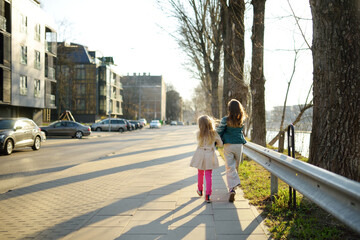 Fototapeta na wymiar Two cute young sisters having fun together on beautiful spring day in a city. Active family leisure with kids.