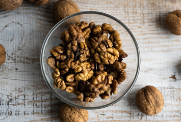 Walnut in a smale plate with scattered shelled nuts and whole nut which standing on a wooden vintage table. Walnuts is a healthy vegetarian protein nutritious food. Walnut on rustic old wood.