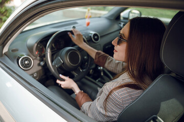 Naklejka na ściany i meble Beautiful young girl sitting behind the wheel of a luxury car