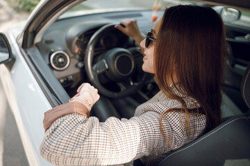 Beautiful young girl sitting behind the wheel of a luxury car