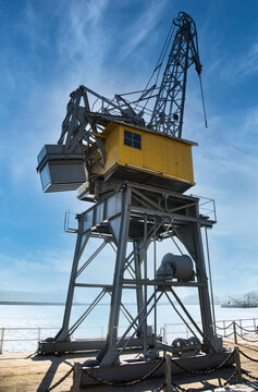 Low angle of contemporary container crane located on quay in Port of San Esteban de Pravia against cloudy blue sky on sunny day in Spain