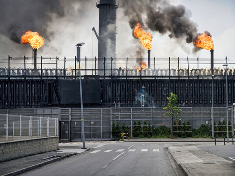Weathered industrial buildings and pipes emitting smoke and flames at coking factory