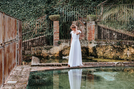 Young bride near shabby fence and pool