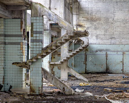 Concrete walls and remains of stairways in old abandoned industrial building with messy ground