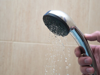 Man's hand show in faucet dirty shower head. There are broken with low stream. Mad spa item need clean up.