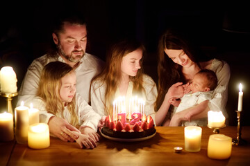Obraz na płótnie Canvas Cute twelve years old girl making a wish before blowing candles on her birthday cake. Child celebrating her birhday.
