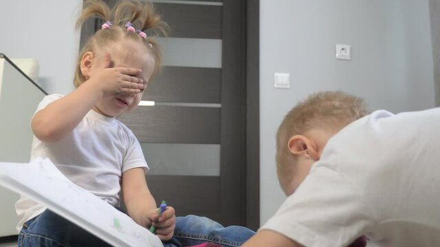 happy family a brother and sister teamwork concept. little boy and girl draw on floor in sketchbook. brother and sister in the room draw lifestyle with crayons