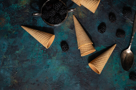 Waffle horns with blackberry berries with hard creative light with space for an inscription, creative photo