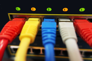 multi-colored network patch cords connected to a switch with lit indicators