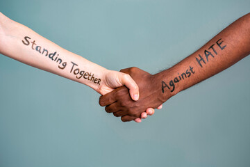 Handshake between black and white human woman and male hands with the message text Standing...