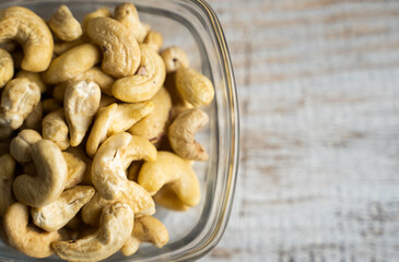 Cashew nuts in a small plate on a vintage wooden table as a background. Cashew nut is a healthy vegetarian protein nutritious food.