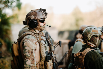 Side view of adult man in military uniform and with airsoft gun listening to briefing with squad