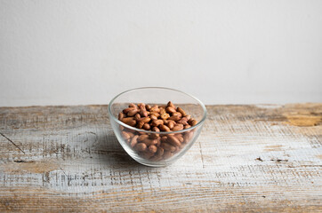 Peanut nuts in a small plate on a vintage wooden table. Peanuts nut is a healthy vegetarian protein nutritious food.