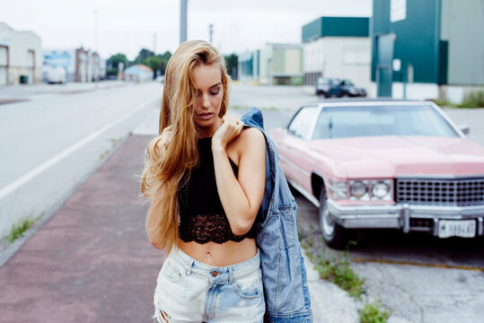 Attractive blonde girl standing on the sidewalk and messing with her hair