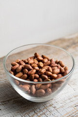 Peanut nuts in a small plate on a vintage wooden table. Peanuts nut is a healthy vegetarian protein nutritious food.