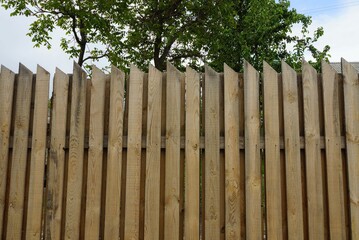 private long brown  fence from wooden boards on a rural street