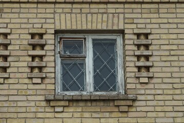 one white old wooden window with iron bars on the brown brick wall of the building